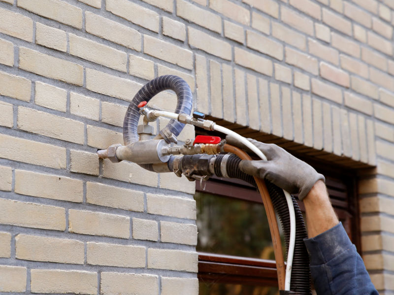 Hausfassade wird mit Einblasverfahren einer Kerndämmung unterzogen